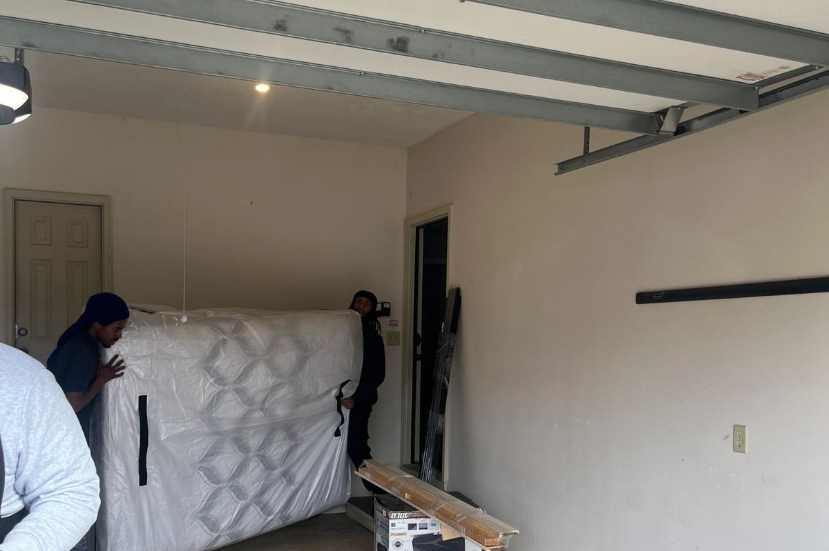 Two God's Movers crew members moving a large safe on a dolly